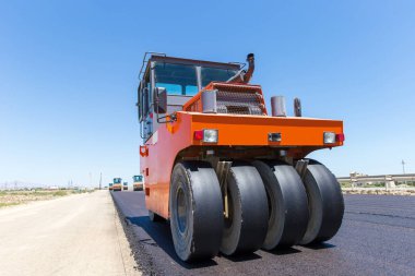 Yol silindiri bulutlu mavi gökyüzü ile yol inşaat sahasında