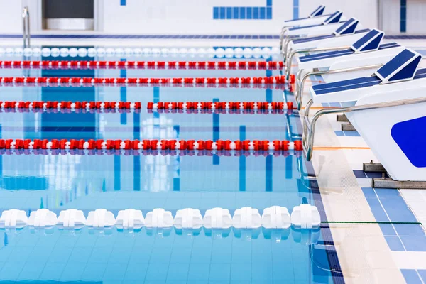 Swimming pool with marked red and white lanes. Empty swimming pool without people with quiet standing water. Water sports in indoor pool.