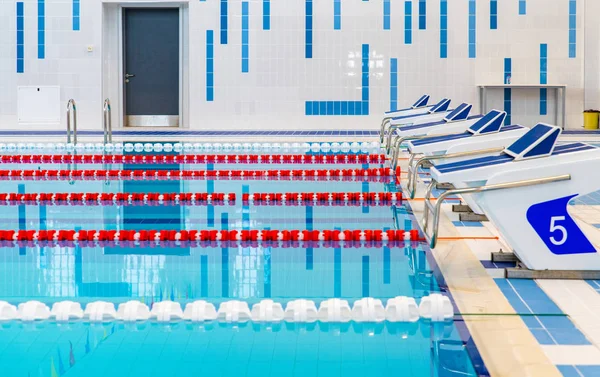 Swimming pool with marked red and white lanes. Empty swimming pool without people with quiet standing water. Water sports in indoor pool.