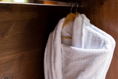 Şık bir banyoda ahşap askıları iki beyaz bez bornoz havlu.
