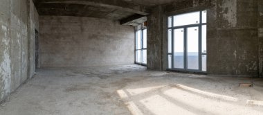 İçi tamamlanmamış bina. Apartmanda tamirat var. Geniş bir oda, pencerelerden gelen doğal ışıkla aydınlatılmış..
