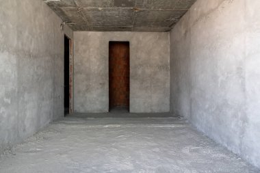 İçi tamamlanmamış bina. Apartmanda tamirat var. Geniş bir oda, pencerelerden gelen doğal ışıkla aydınlatılmış..