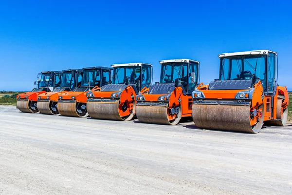 Asphalt road-rollers on parking lot. Red road rollers parked on the unfinished road construction site