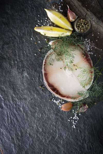 A shark steak with herbs and lemon. Dark background