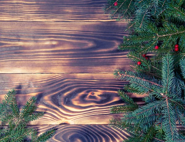 Karácsonyi üdvözlőlap, fenyőtoboz. Fenyőfa ágakból és fenyőtobozokból készült keret, vörös bogyó, fa barna felületen. Karácsony, tél, újévi koncepció. Lapos fekvés, csúcskilátás. másolás helye. — Stock Fotó