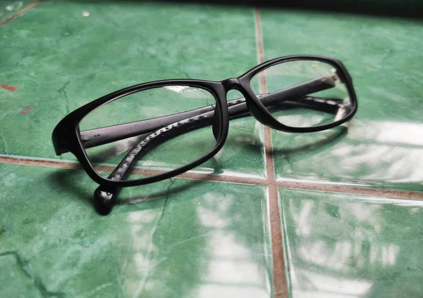 Yeşil zeminde bir çift siyah gözlük.