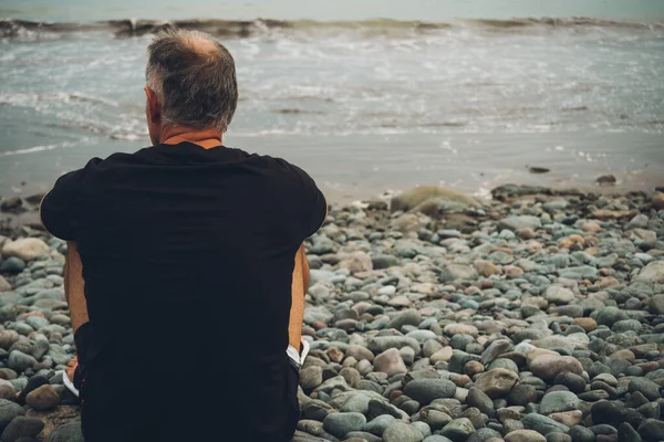 man look at the sea sitting on the beach