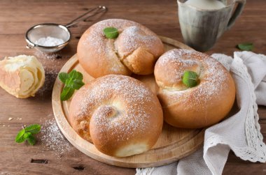 Tahta bir masada pudra şekerli çörekler ve süt.