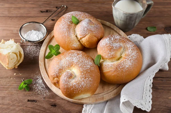 Buns met poedersuiker en melk op een houten tafel — Stockfoto