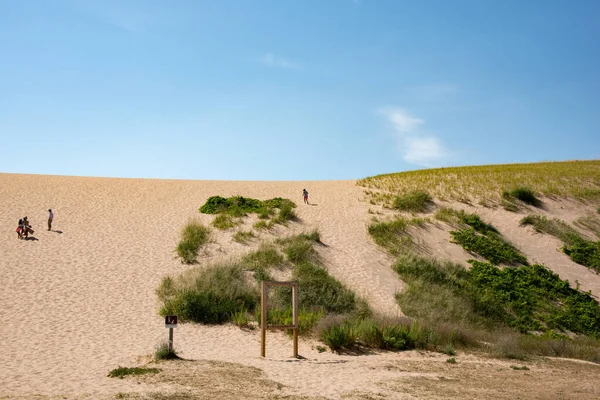 Tourists climbing up and down a popular dune, dune overlooking Sleeping Bear Dunes National Beach. Panorama.