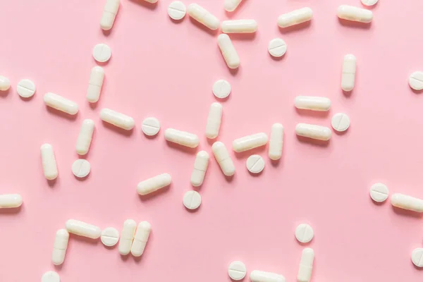 Fondo rosa con comprimidos y píldoras blancas . — Foto de Stock