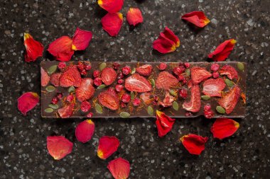 Kurutulmuş çilek ve kızılcık gül yaprakları ile el yapımı çikolata bar.