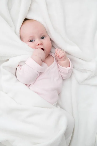 Niña acostada en la cama, recién nacido cubierto por una manta blanca, espacio para copiar —  Fotos de Stock