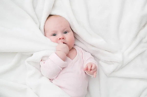 Niña acostada en la cama, recién nacido cubierto por una manta blanca, espacio para copiar — Foto de Stock