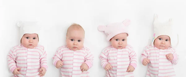 Lindo niño adorable bebé con diferentes sombreros blancos y rosados cálidos. Feliz niña sobre fondo blanco y mirando a la cámara . — Foto de Stock