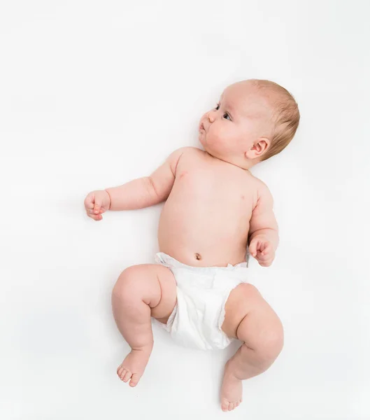 Una linda niña de cuatro meses con una cubierta de pañal blanca se acuesta sobre un fondo blanco . —  Fotos de Stock