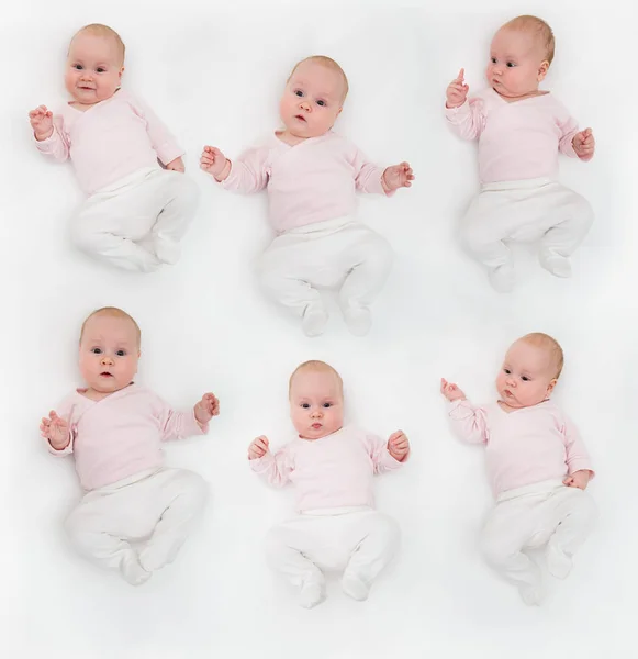 Conjunto de bebé muy feliz en traje de cuerpo blanco y rosa acostado sobre su espalda en el blanco. Bebé mirando directamente a la cámara . — Foto de Stock