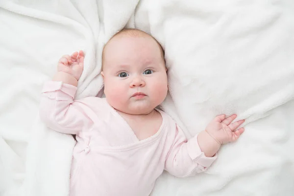 Niña está acostada sobre una manta blanca — Foto de Stock