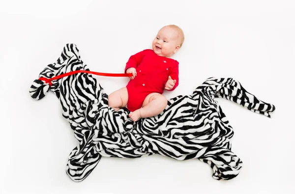 Un niño de cuatro meses monta una cebra desde un paño en el suelo — Foto de Stock