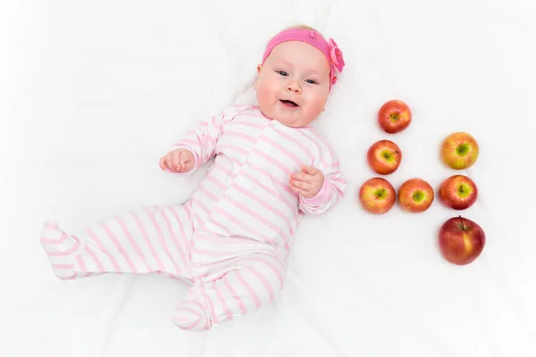 Linda niñita acostada sobre fondo blanco con manzanas rojas y verdes frescas en forma de número cuatro — Foto de Stock