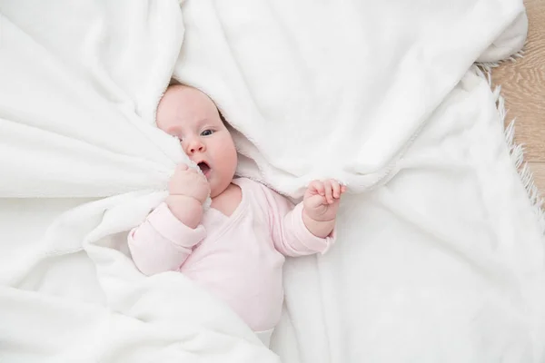 Niña acostada en la cama, recién nacido cubierto por una manta blanca, espacio para copiar — Foto de Stock