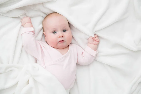 Niña acostada en la cama, recién nacido cubierto por una manta blanca, espacio para copiar — Foto de Stock