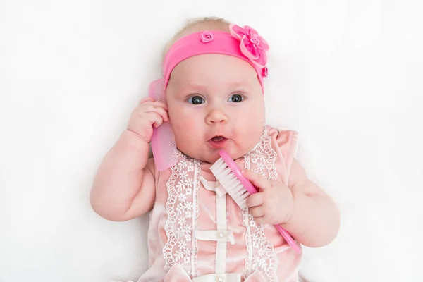 Lindo bebé jugando con un cepillo de pelo sobre fondo blanco — Foto de Stock