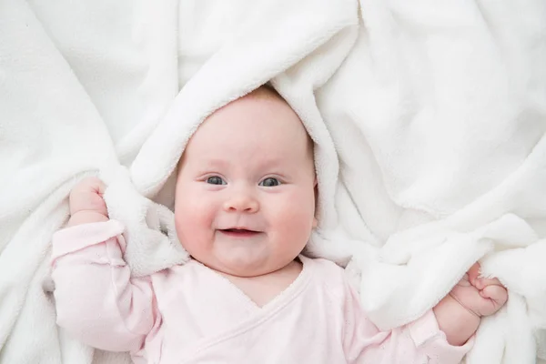 Niña está acostada sobre una manta blanca — Foto de Stock