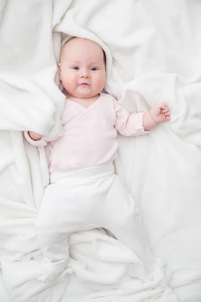 Niña está acostada sobre una manta blanca — Foto de Stock