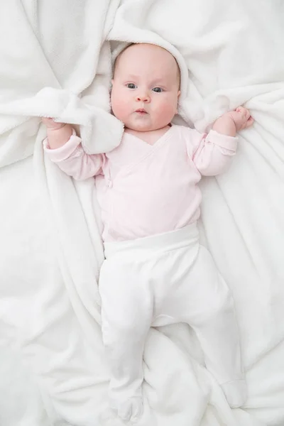 Niña está acostada sobre una manta blanca — Foto de Stock