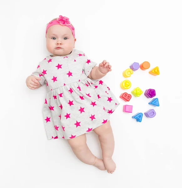 Portret słodkiej niemowlęcia dziewczynka ubrana w różowy strój i łuk pałąka, izolowane na białym w Studio z numerem szóstym z zabawek — Zdjęcie stockowe