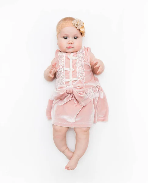 Portret słodkiego niemowlęcia ubrany w różową sukienkę, łuk pałąka na białym tle w studiu. — Zdjęcie stockowe