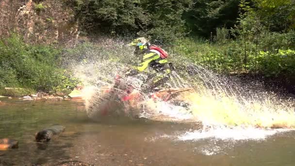 Le motocycliste d'Enduro traverse la rivière Mountain Splashes of Water and Dirt. Mouvement lent .
