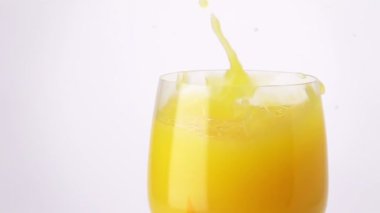 Bir bardak portakal suyuna dökülen portakal dilimleri, damlalar. Yavaş Hareket.