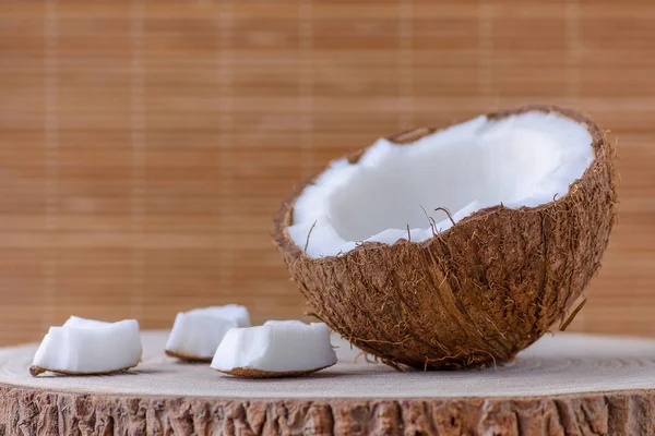 Une moitié de noix de coco et des morceaux sur fond brun — Photo