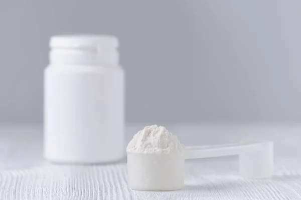 bir kaşık beyaz toz ve bir plastik şişe gri, seçici odak ile