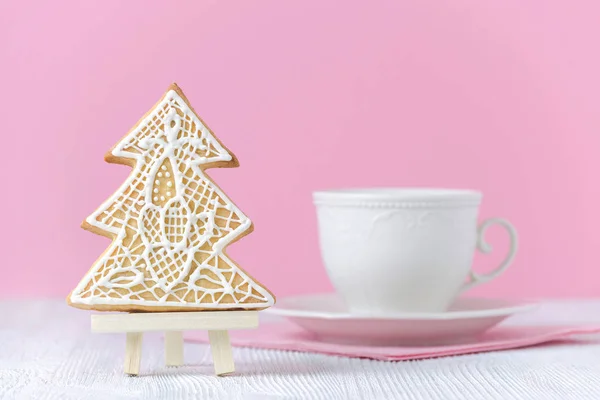 Christmas tree gingerbread on the painting easel with coffe cup on pink background — Stock Photo, Image