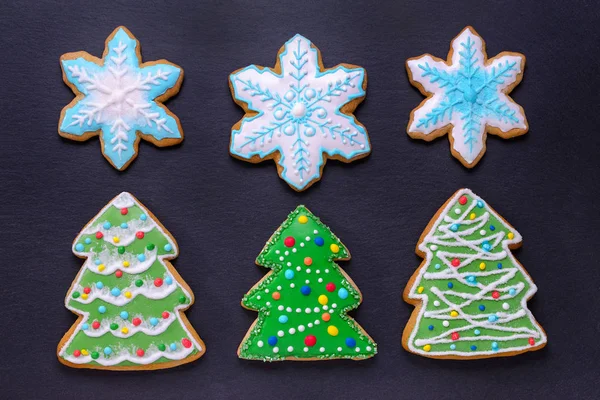 Comida de Navidad, galletas hechas a mano pan de jengibre como árboles de Navidad y copos de nieve sobre fondo negro — Foto de Stock