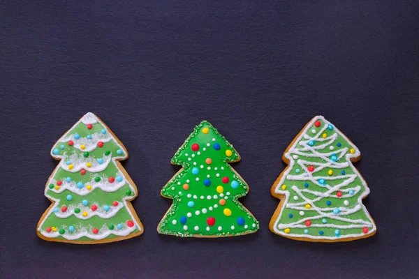 Handmade cookies like decorated christmas trees on dark with copy space — Stock Photo, Image