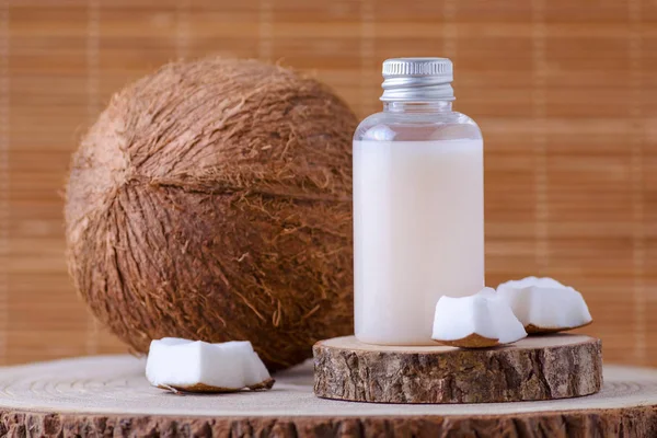 Cosmetische fles en verse biologische kokosnoot, natuurlijke achtergrond — Stockfoto