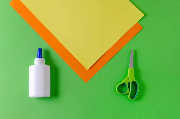 Papel a cores amarelo, cor-de-laranja e cola com tesoura para diy em verde — Fotografia de Stock