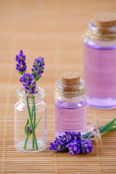 Levandulový olej v lahvích a čerstvé levandulové květy na dřevěné pozadí — Stock fotografie