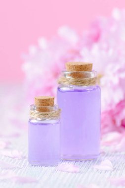 aroma yağları, pembe bir arka plan, seçici odak üzerinde taze çiçekler iki şişe ile güzel spa kompozisyon