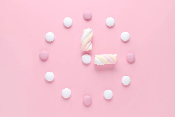 Concept image, une horloge avec des bonbons et guimauve, couleurs pastel sur rose — Photo