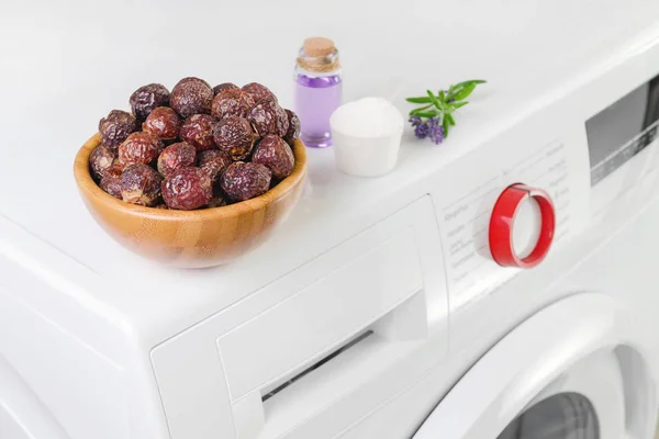 Soap nuts in a bowl on the washing machine and lavender oil, detergent powder, selective focus — Stock Photo, Image