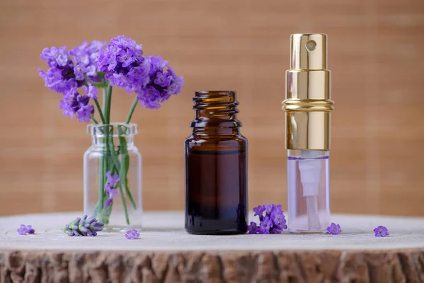Lavanta esansiyel yağ ve su şişe ve taze lavanta çiçekleri için kahverengi relax arka plan üzerinde seçici odak