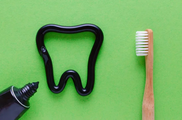 Зуб из зубной пасты, концепция ухода за зубами, зубная щетка на зеленом фоне — стоковое фото