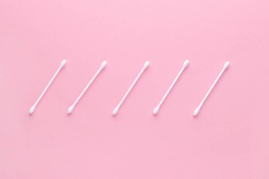 Pembe arka planda beyaz pamuk çubukları, düz bez