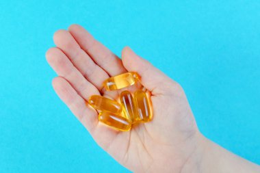 mavi arka plan üzerinde omega kapsülleri ile çocuk el