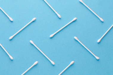 Mavi arkaplanda beyaz pamuklu çubuklar, soyut desen, yakın plan.